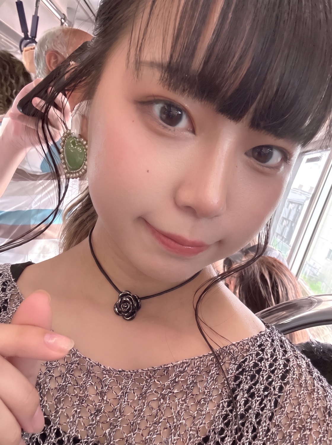 Mio, a host with blunt bangs and a rose choker, taking a selfie on a Tokyo train.